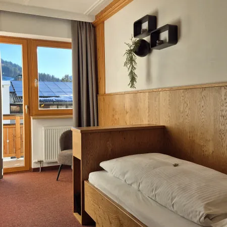 Holzvertäfelter Raum mit Bett, Fenster und Pflanzen an der Wand