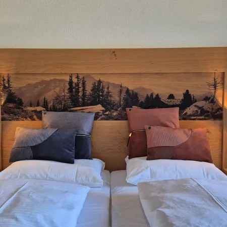 Doppelbett mit Holzkopfteil und Kissen in verschiedenen Farben
