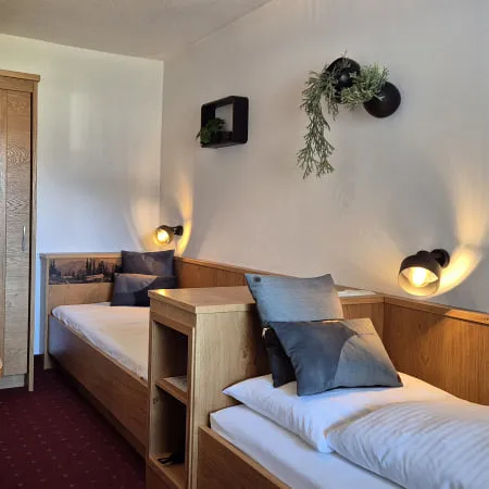 Ein Zwillingzimmer mit zwei Betten, einem Tisch und Wandpflanzen.