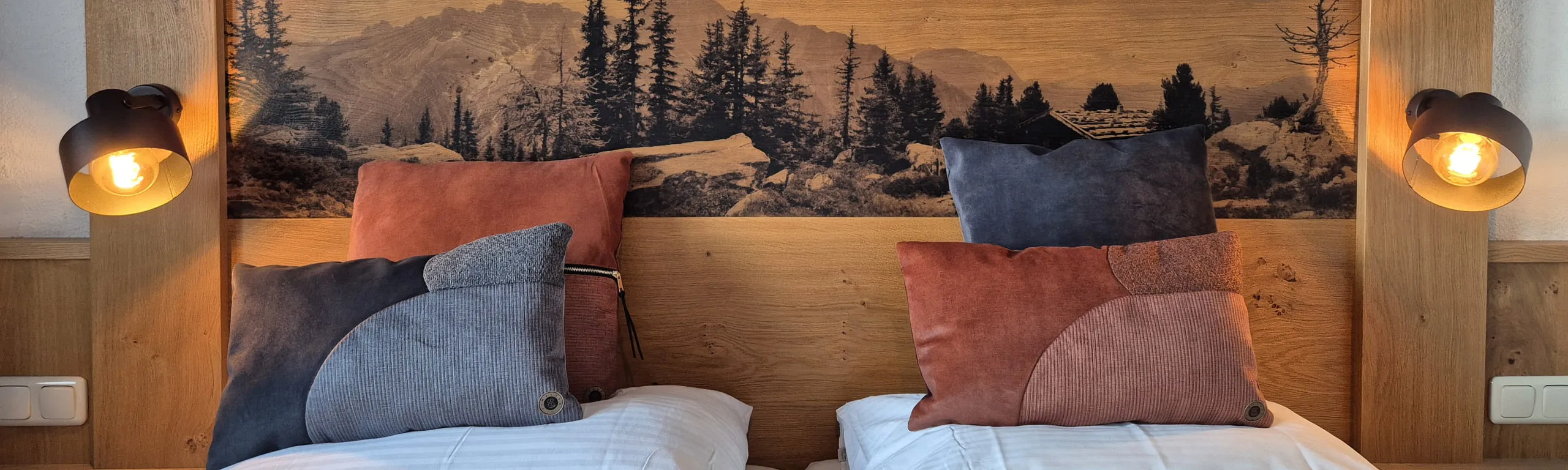 Twee bedden met decoratieve kussens en een boslandschap op de achtergrond