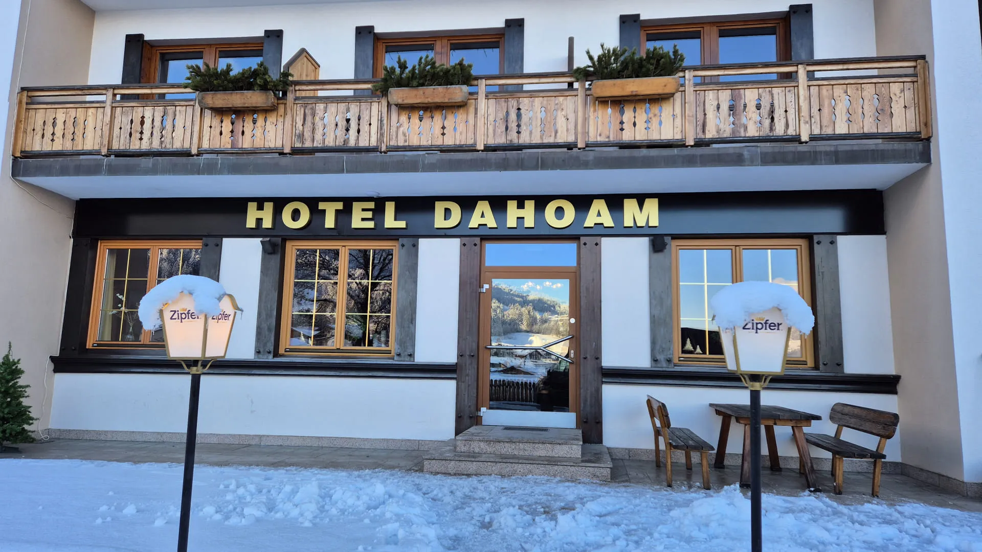 Hotel Dahoam met balkon en zitgedeelte in de sneeuw.