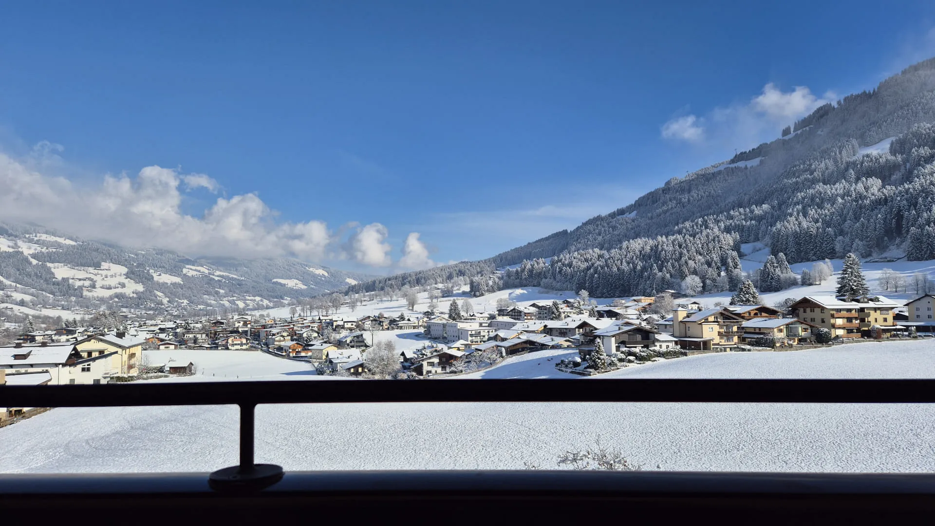 Uitzicht op een besneeuwd dal met huizen en bergen op de achtergrond