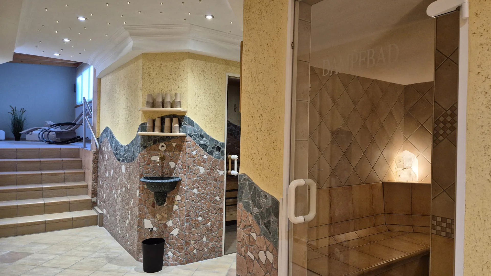 Een saunagebied met tegels, een sauna en trappen.