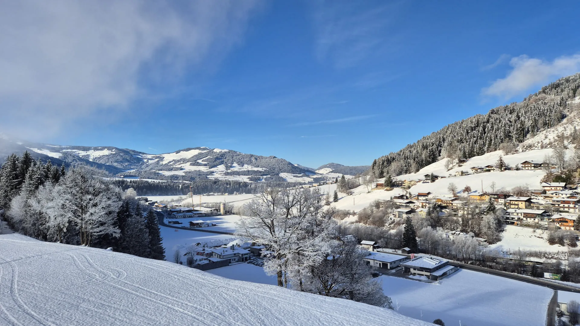 Sneeuwbedekt uitzicht op een vallei met bergen en een heldere blauwe lucht