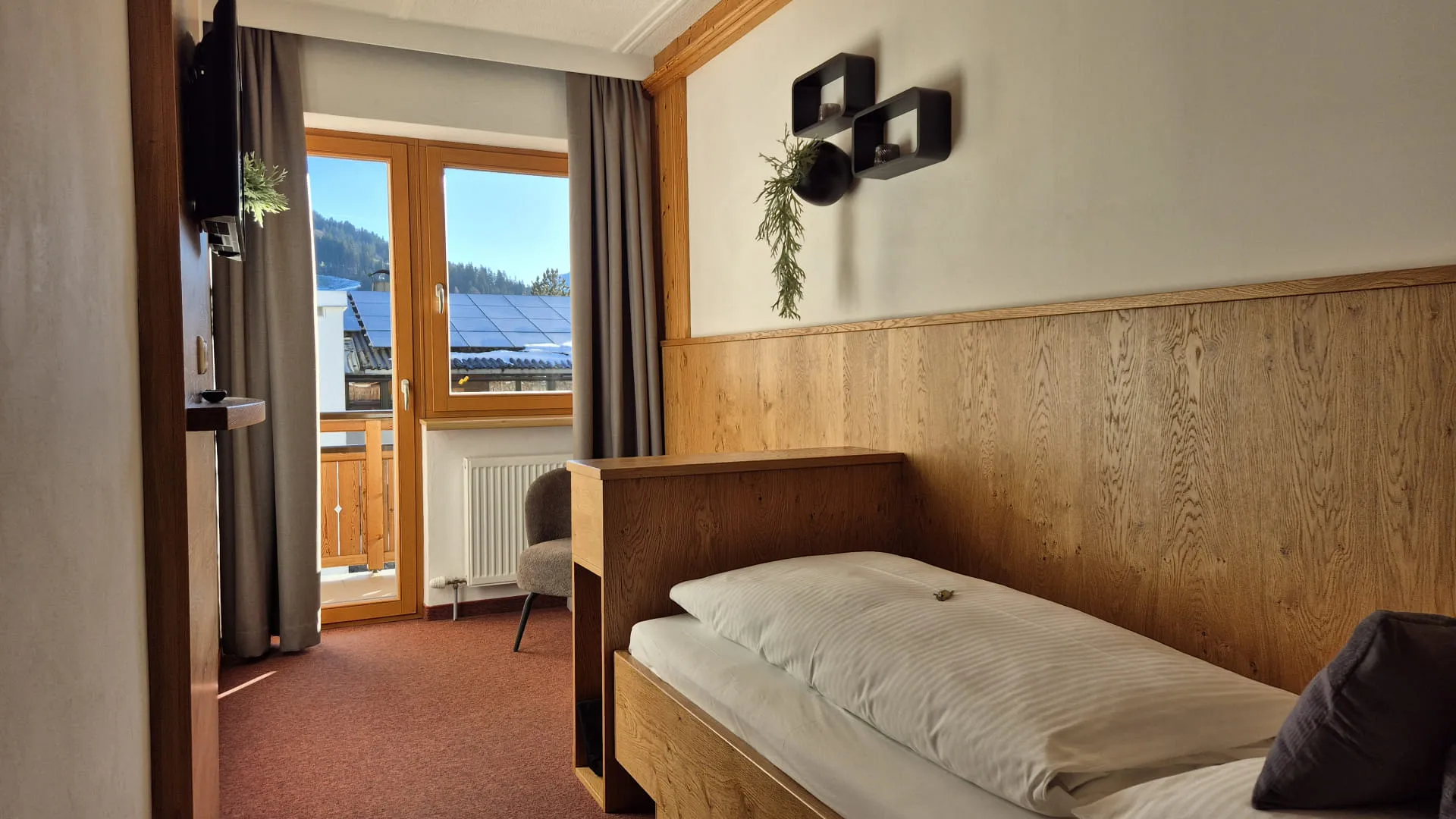 Heldere kamer met houten decor, bedden en een raam met uitzicht.