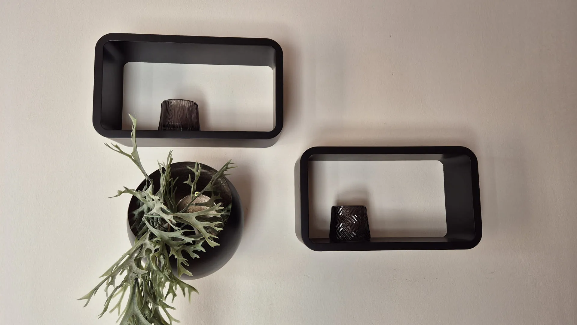 Twee zwarte wandplanken met een plantenpot