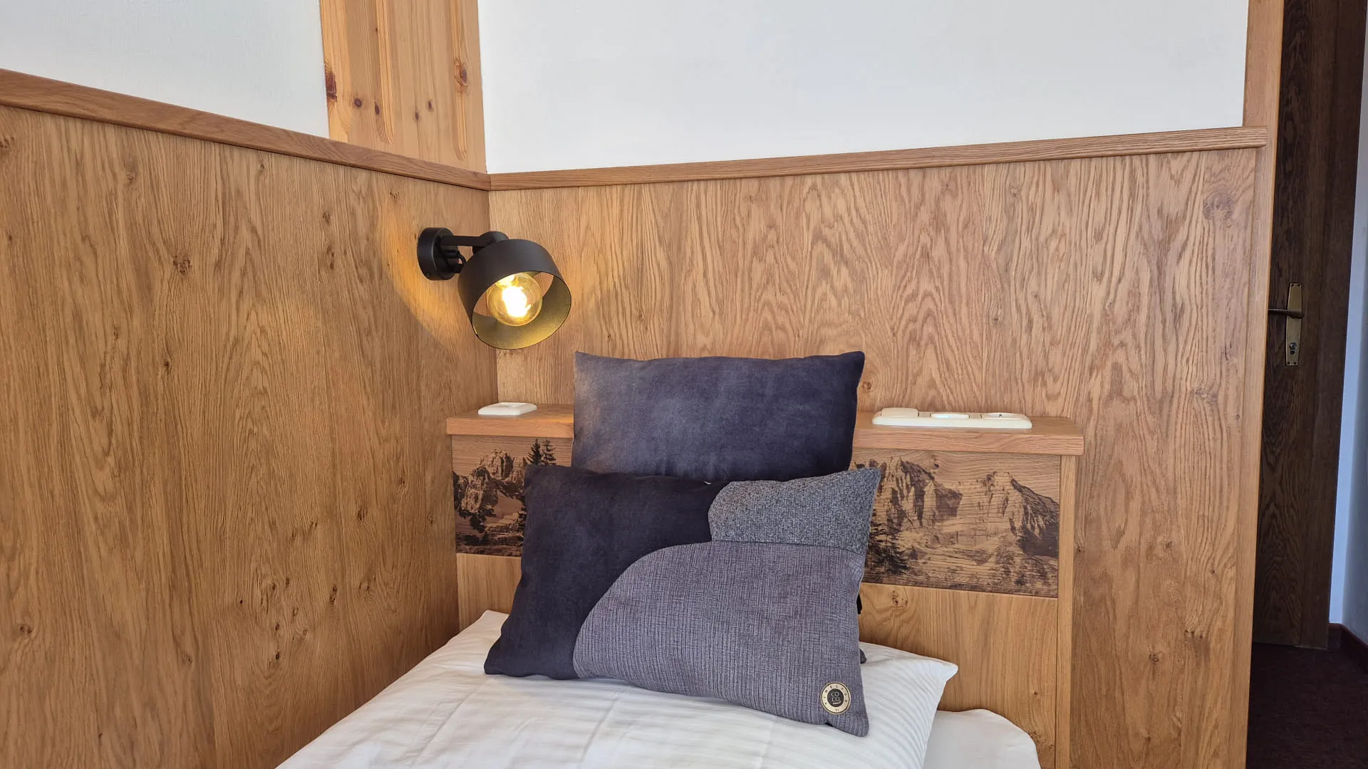 Houten wand met lamp en kussens op het bed