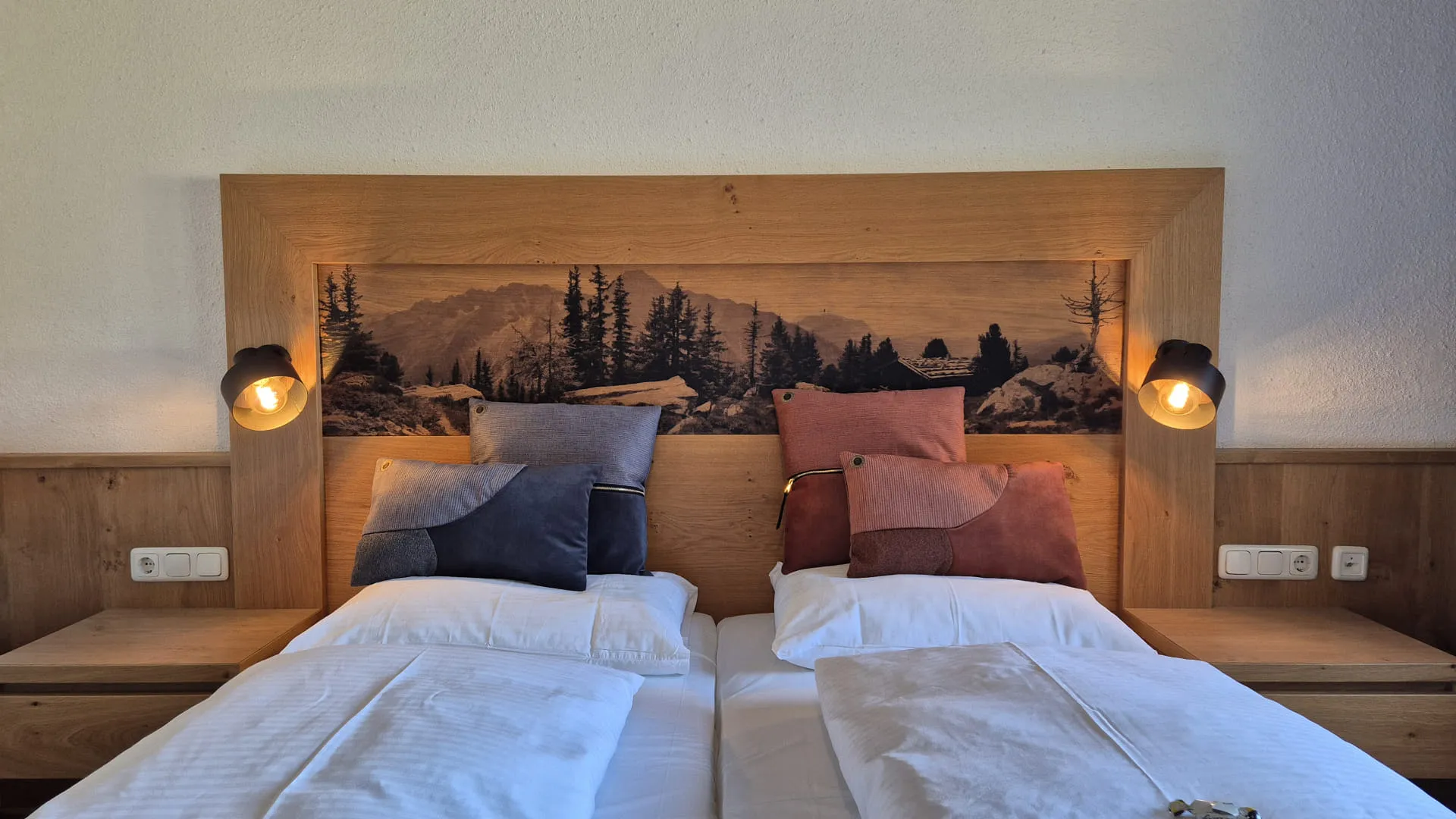 Zwei Einzelbetten mit Holz Kopfteil und Landschaftsmotiv.