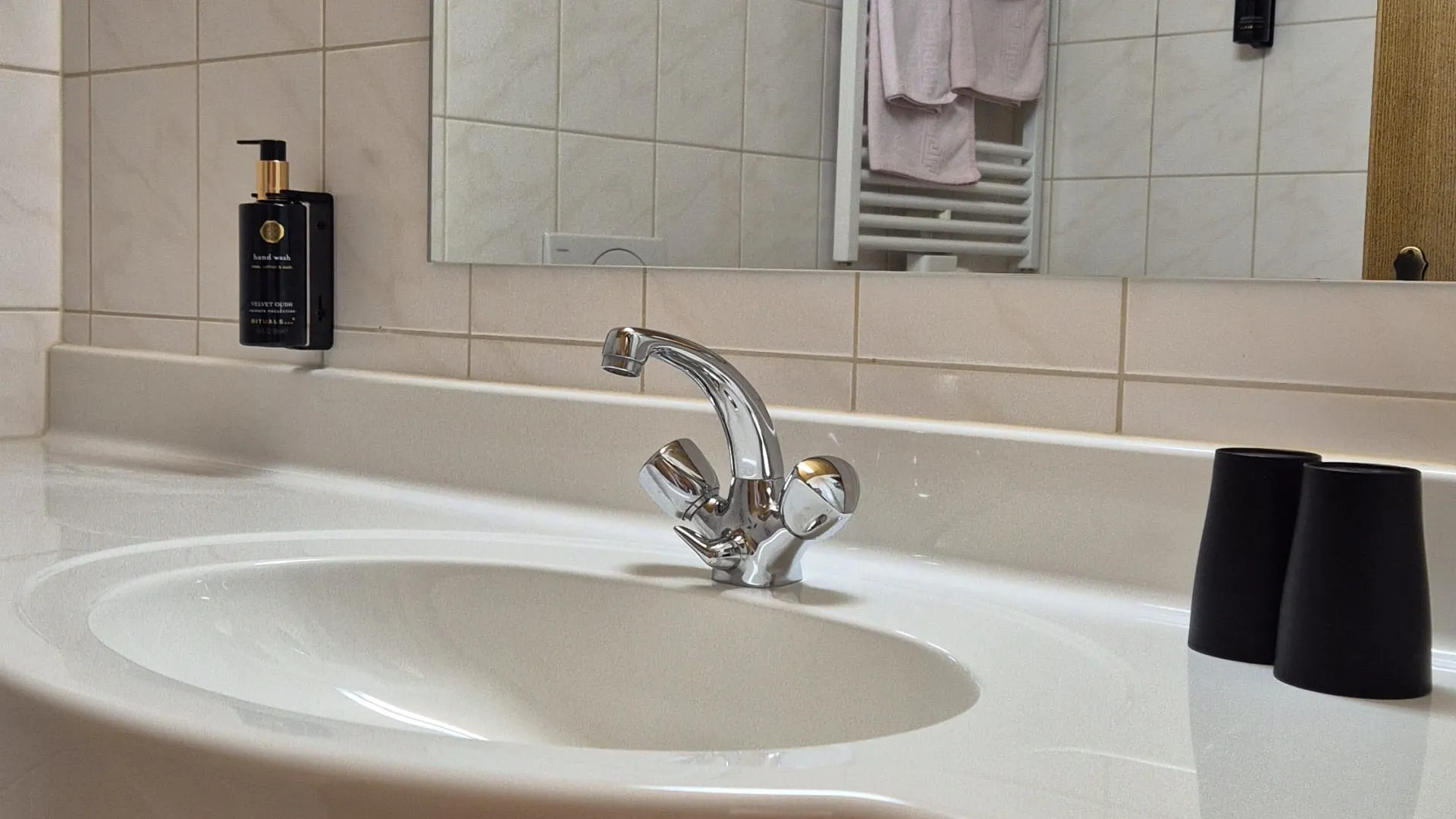 Badezimmerwaschtisch mit Spiegel und Handtüchern im Hintergrund