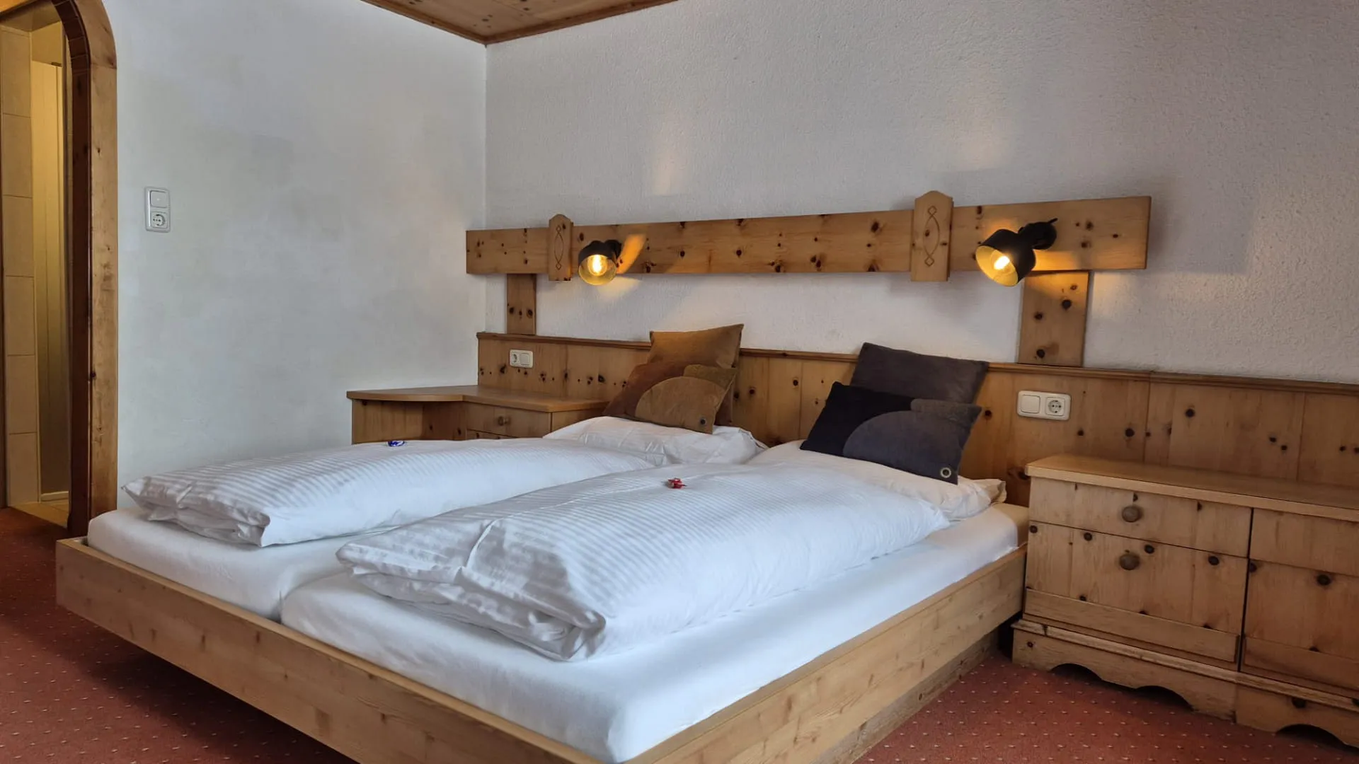 Houten bed met witte beddengoed en nachtlampjes in een kamer