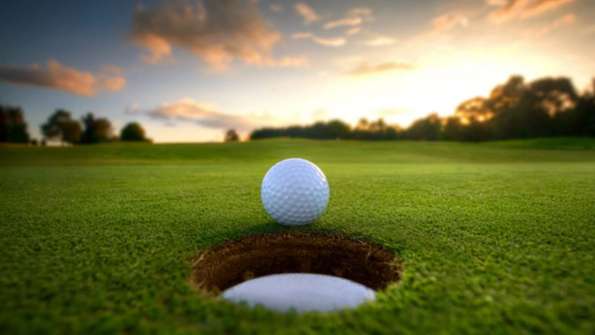 Ein Golfball in der Nähe eines Lochs auf einem Golfplatz bei Sonnenuntergang